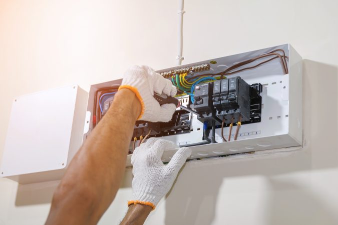 Closeup of hands of electrician using a screwdriver to tighten the circuit breaker to prevent power supply to the control box.